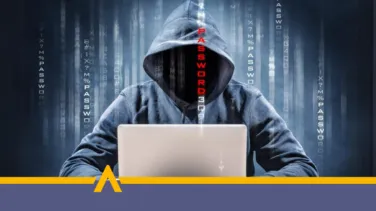 Haker w kapturze przy laptopie próbujący włamać się do systemu