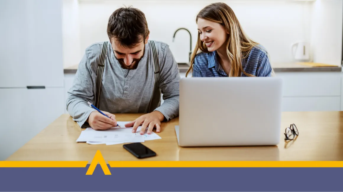 Uśmiechnięta para podpisująca dokumenty przy laptopie