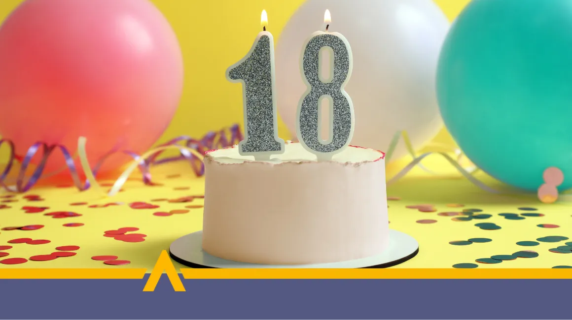 Tort urodzinowy z świeczkami w kształcie liczby 18, w otoczeniu kolorowych balonów i konfetti.
